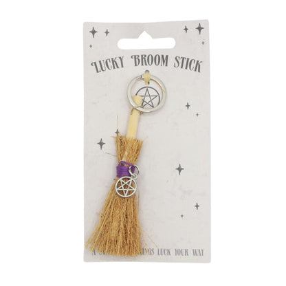 tiny broomstick, with a purple string and a pentacle charm attached to it on a silver keyring