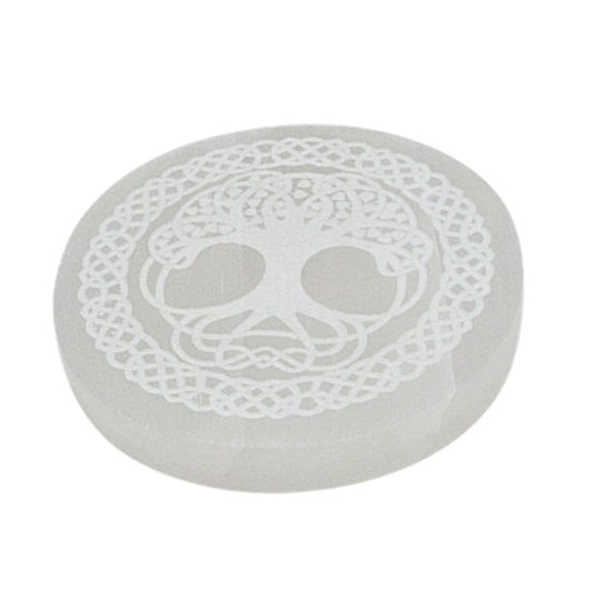 Round selenite charging stone with a tree of life design on a white background