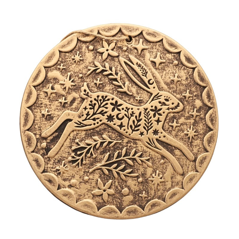 round gold plaque with a leaping hare and floral design