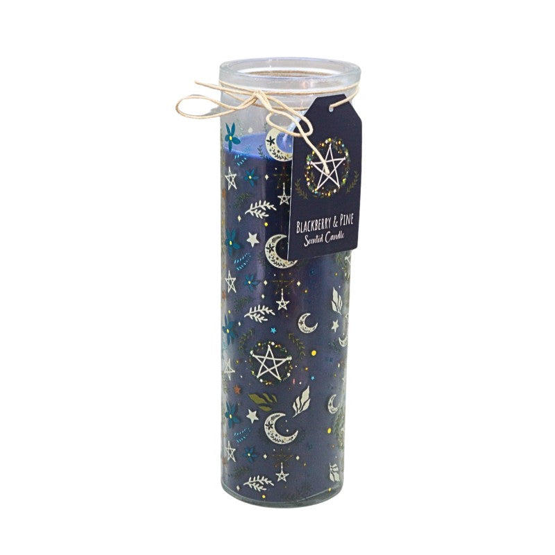 A tall glass jar candle filled with dark blue wax and decorated with a celestial pattern of stars, moons, and leaves in metallic gold and silver. A black paper tag with a pentagram design is attached to the neck with a string bow, set against a plain white background.