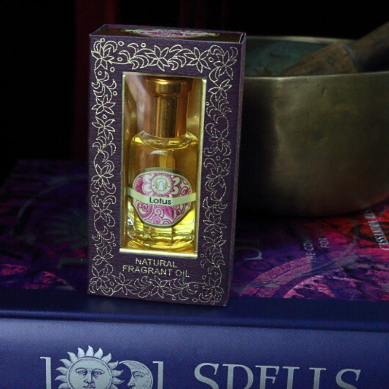Lotus Song of India Perfume Oil sitting on a book of spells in front of a singing bowl