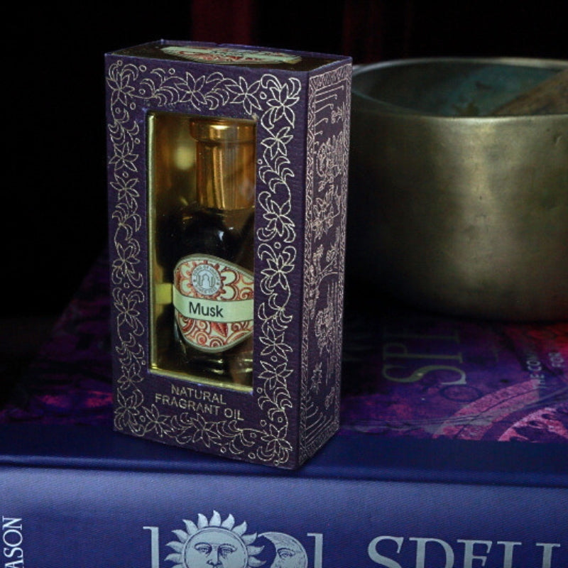 Musk Song of India Perfume Oil sitting on a book of spells in front of a singing bowl