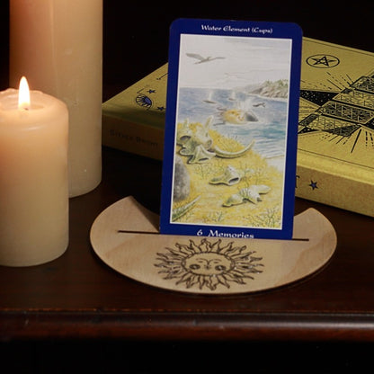 handmade tarot card holder with sun  design, in front of a tarot book with candles in the background