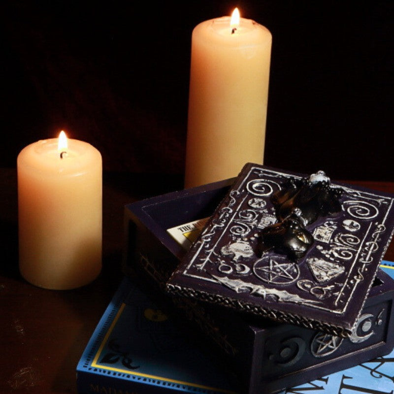 Black Cat Tarot Card Storage Box with a pack of pocket sized rider waite tarot cards in front of beeswax candles on a tarot book