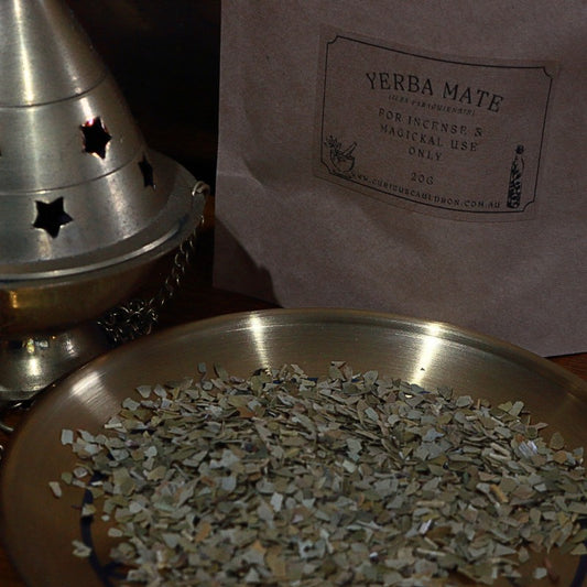 Yerba Mate leaves on a metal tray with a metal cone and packaging in the background.