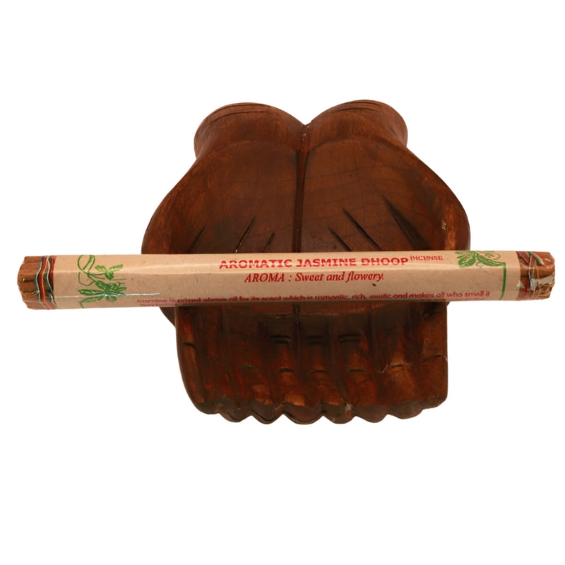 pk of hand rolled tibetan incense sitting on a statue of carved wooden hands