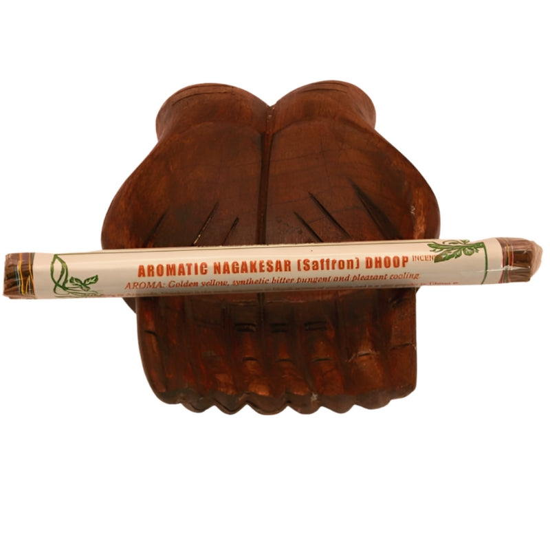 pk of hand rolled tibetan incense sitting on a statue of carved wooden hands