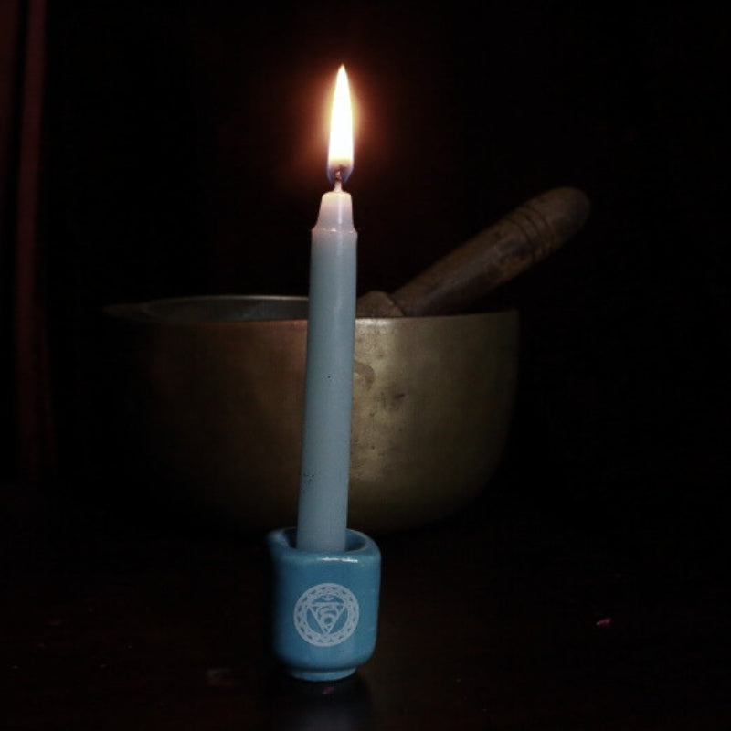 blue candle in throat chakra spell candle holder in front of singing bowl