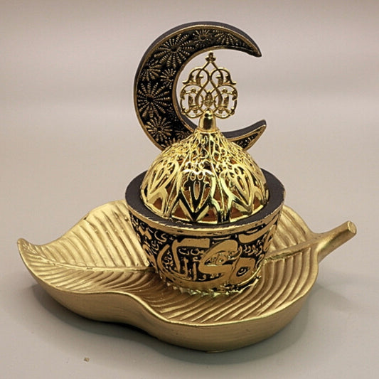 black and gold incense burner in the shape of a crescent moon on a gold leaf