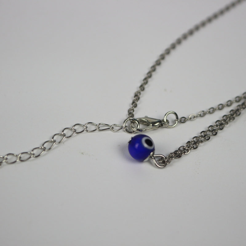 silver necklace with a blue, white and black eye shaped bead n a white background