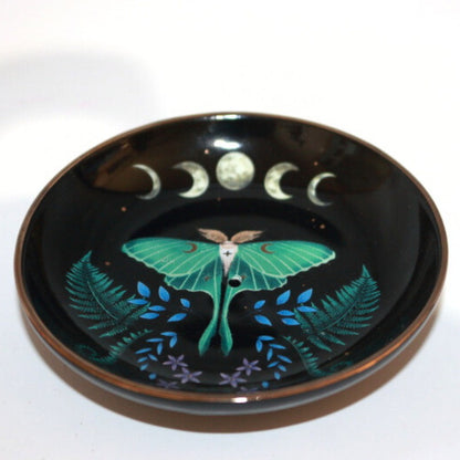 black incense dish with a luna moth and ferns under a picture of the moon phases.