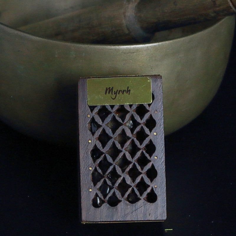 rosewood cutwork box containing myrrh resin standing in front of a brass singing bowl