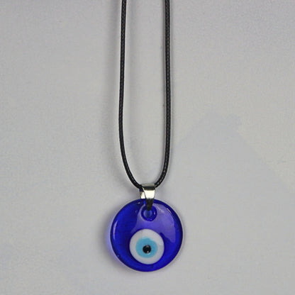 blue, white, light blue and black concentric circles  formed into an eye shaped bead, hung on a black cord with a silver clasp. The necklace hangs on a light grey wall