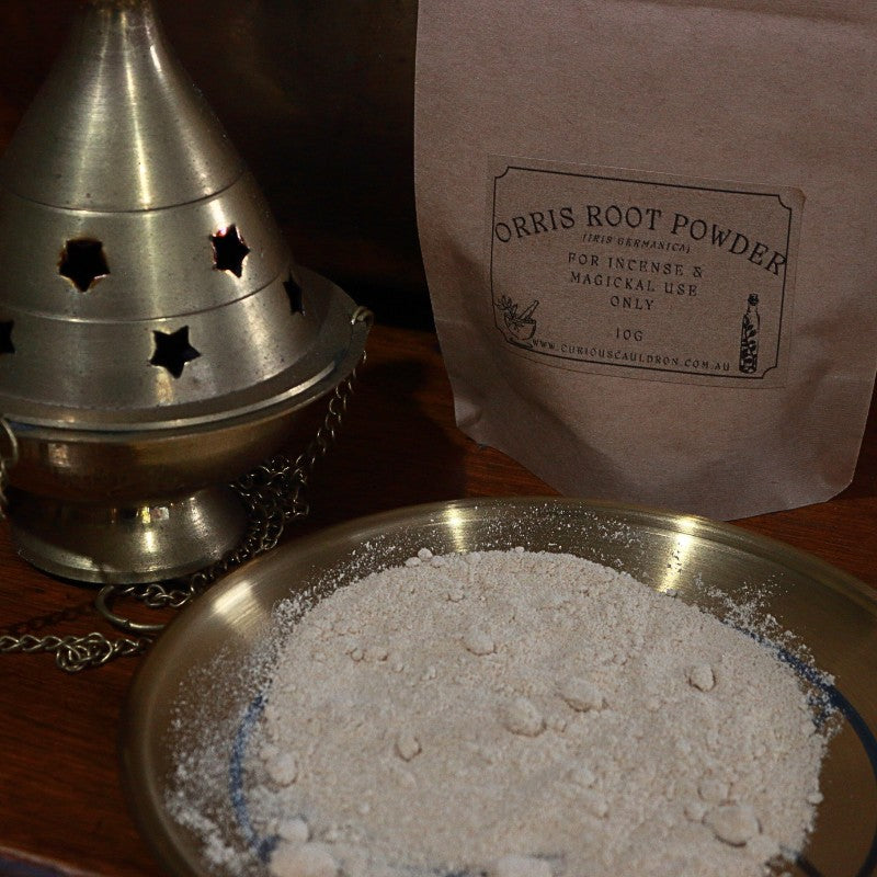 Orris root powder in a bowl with a brass cone incense burner and a bag labeled 'Orris Root Powder' on a wooden surface.