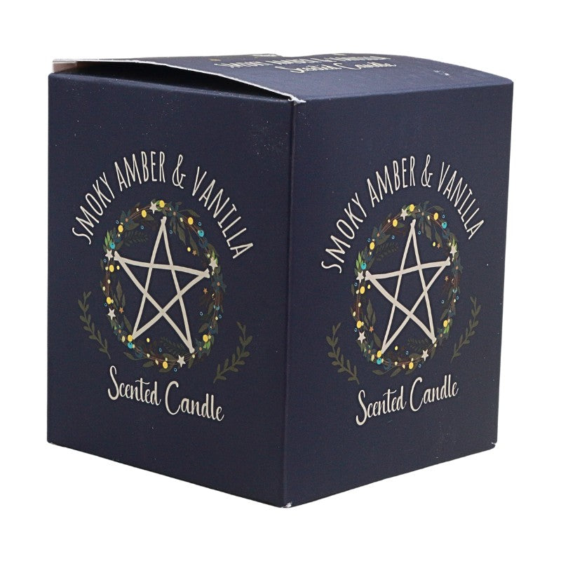 A dark navy blue square cardboard box for a scented candle, featuring a white pentagram inside a floral wreath with the text 'SMOKY AMBER & VANILLA' and 'Scented Candle'.