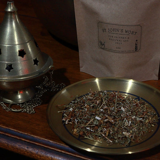 Herbal incense on a metal plate with a metal cone incense burner and a bag labeled 'St. John's Wort' in the background.