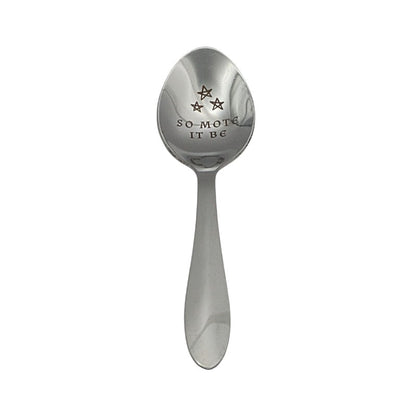 Silver spoon with engraved text 'SO-MOTE IT BE' on a white background
