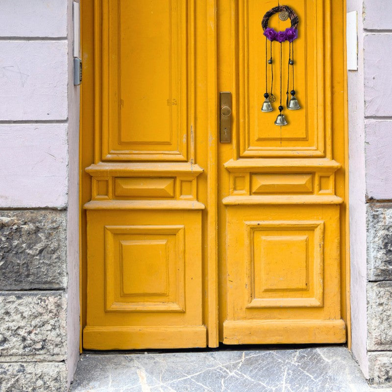 set of witches bells hanging on a yellow door