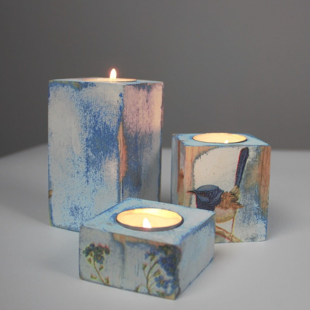 blue and white distressed set of 3 candle holders with lit tea light candles, decorated with  fairy wrens and blue flowers